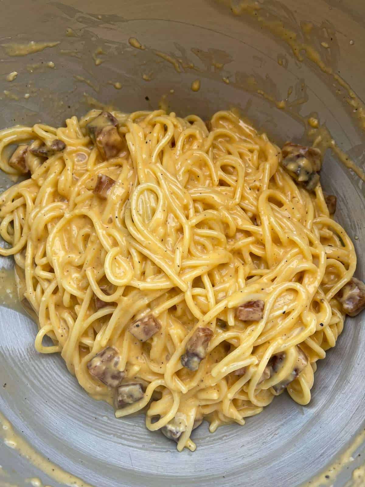 mixing spaghetti carbonara in a bowl