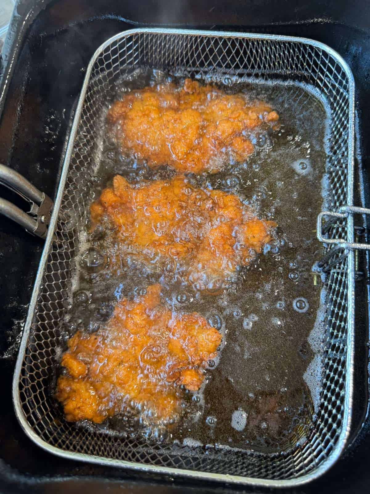 chicken frying in deep fat fryer