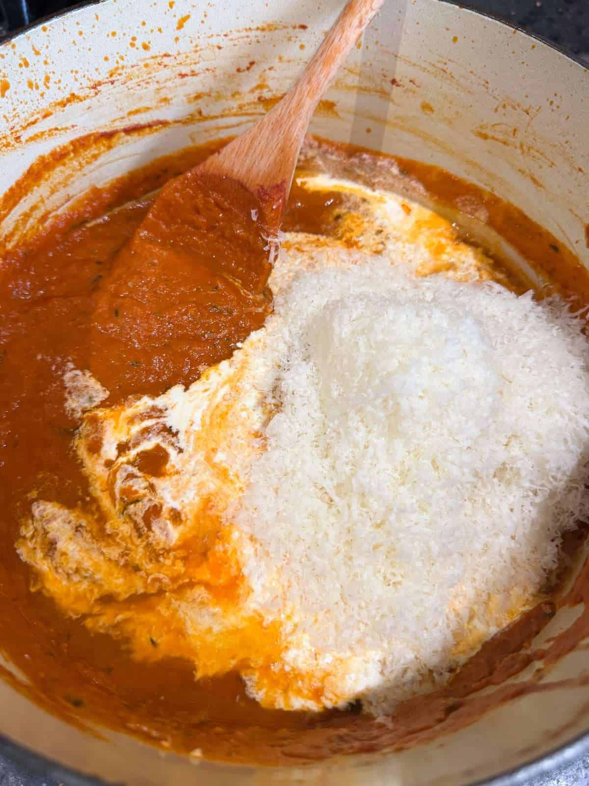 adding cream and vodka to tomato sauce