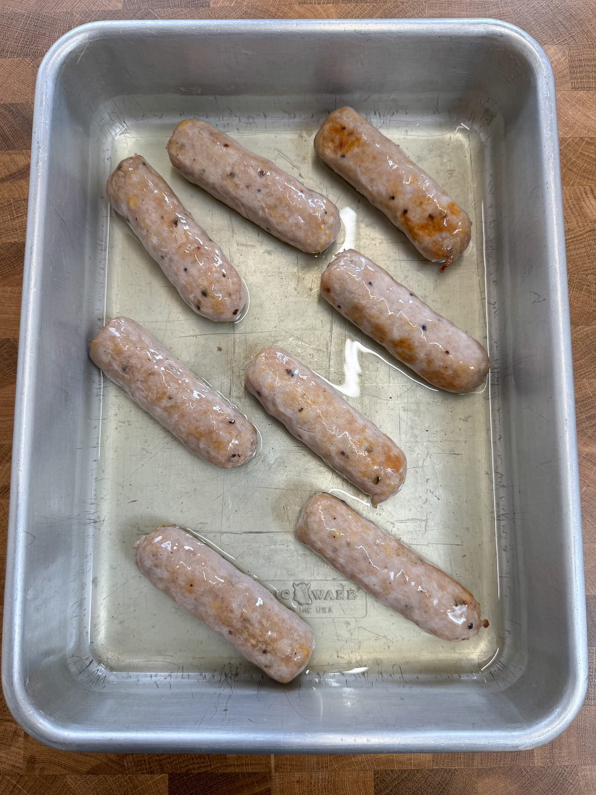 browned sausages in roasting tin