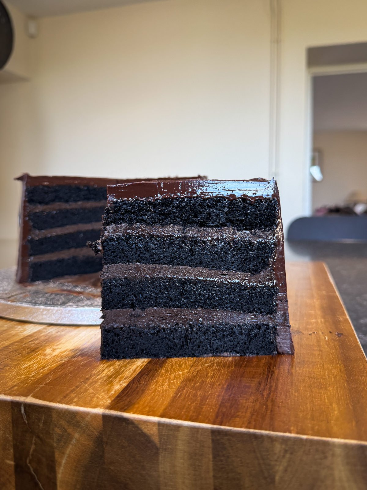 fudge cake slice with whole cake in background
